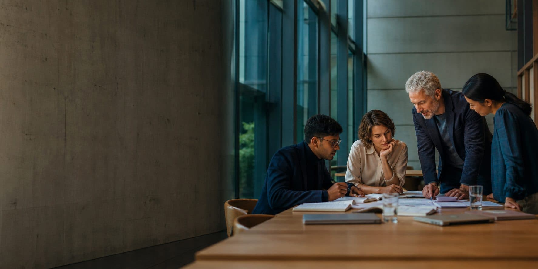 Illustrative scene of four people reviewing documents together around a table